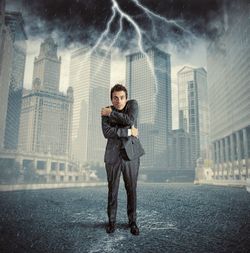 Full length portrait of man standing in city during rainy season