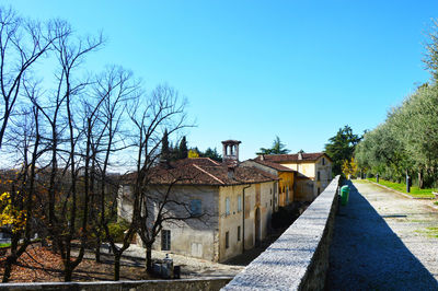 Bare trees and buildings against clear sky