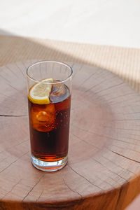 Refreshing cocktail or espresso tonic drink on small wooden table close-up