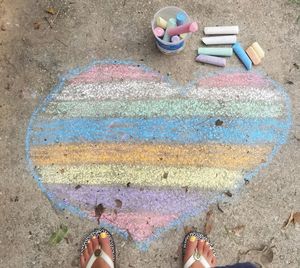 Low section of woman standing by colorful heart shape chalk drawing