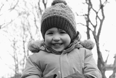 Portrait of smiling girl in warm clothing standing against sky