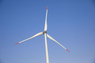 Low angle view of wind turbine against clear blue sky