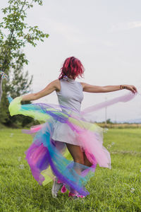 Woman dancing on field against trees