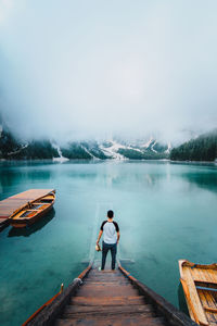 Rear view of man standing on lake against sky