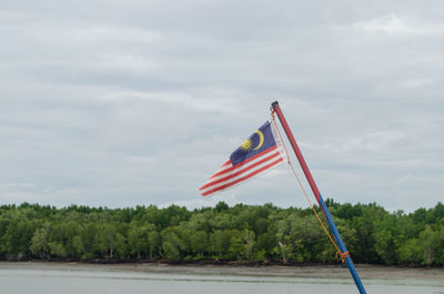 Red flag by trees against sky