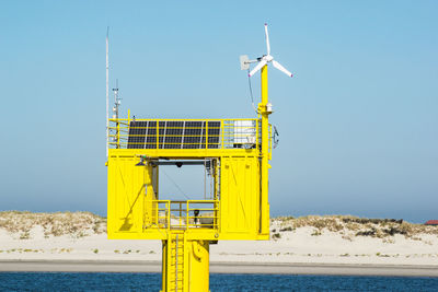 Information sign by sea against clear blue sky