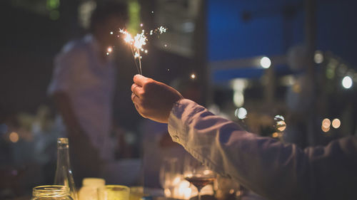 Close-up of hand holding sparkler at night