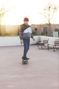 Portrait of boy skateboarding on footpath