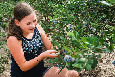 Girl harvesting berries while standing by trees