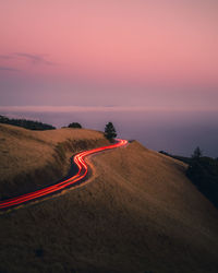 Light trails on road against sky during sunset