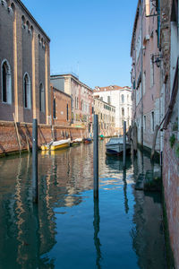 Canal amidst buildings against clear blue sky