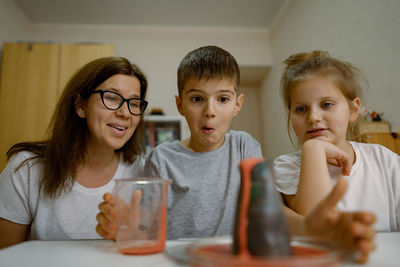 Mom and children at home are conducting an experiment with volcanic eruption.