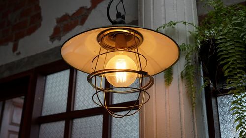 Low angle view of illuminated lamp against wall