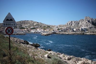 View of townscape by sea against clear blue sky