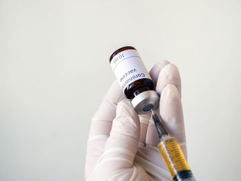 Close-up of hand holding bottle against white background