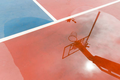 Reflection of basketball hoop at court in puddle