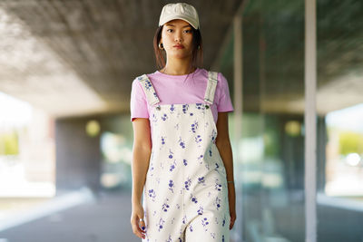 Portrait of young woman standing against wall