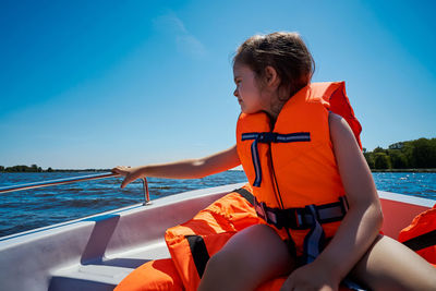 Side view of woman sitting on boat in sea against sky