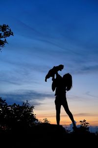 Silhouette woman standing by tree against sky during sunset