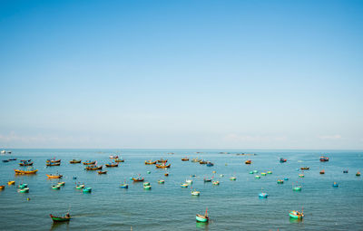 Group of people in sea against clear blue sky