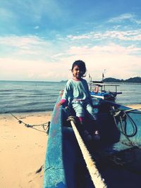 Portrait of girl sitting in boat at beach against sky