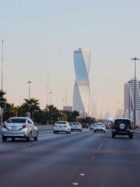 Traffic on road in city against clear sky