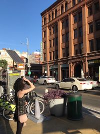 Woman on street against sky in city