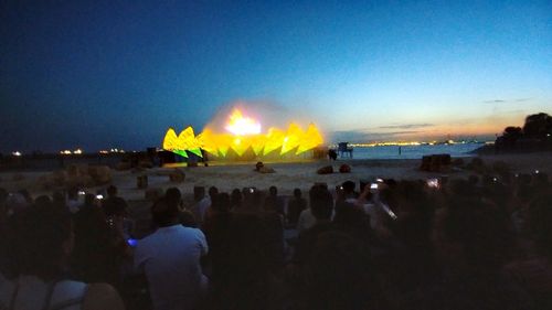 People at illuminated park against clear sky at night