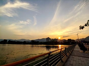 River by city against sky during sunset