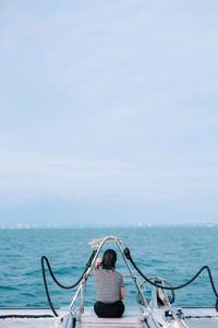 Rear view of woman on sea against sky