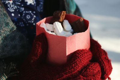 Midsection of person holding marshmallows in paper bag during winter