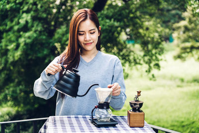 Beautiful woman making coffee on table at yard