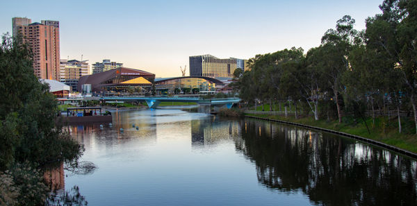 Bridge over river by buildings against clear sky