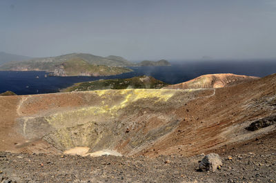 Barren landscape against calm blue sea