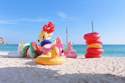 Multi colored toys on beach against sky