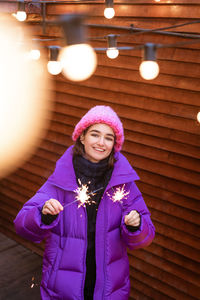 Caucasian girl is having fun in winter on street with sparklers in her hand