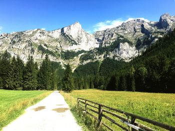 Pathway leading towards mountains against blue sky