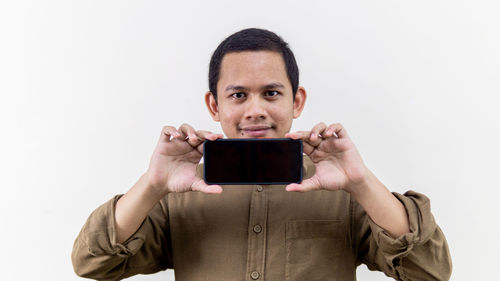 Portrait of young man using smart phone against white background