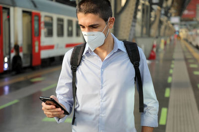 Young man using mobile phone in railroad station