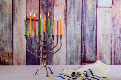 Multi colored illuminated candles against wooden wall