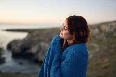 Beautiful woman on beach against sky during sunset