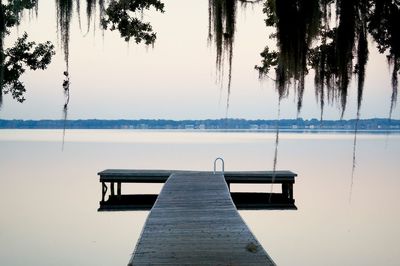 Empty bench by lake against sky