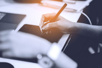 Midsection of woman using graphics tablet at desk in office