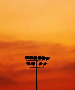 Low angle view of floodlight against orange sky