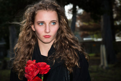 Teenage girl with red flowers looking away at park