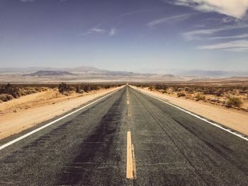 Empty road along landscape against sky