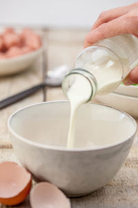 Cropped image of hand pouring milk in bowl