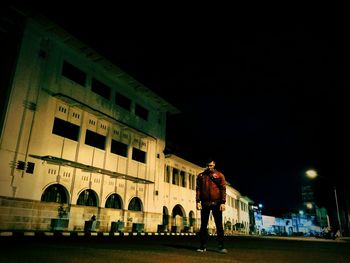 Rear view of man standing in city at night