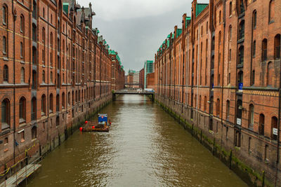 Canal amidst buildings in city against sky