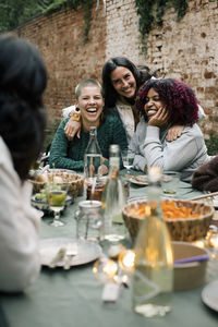 Happy female friends enjoying together at dining table during dinner party in back yard